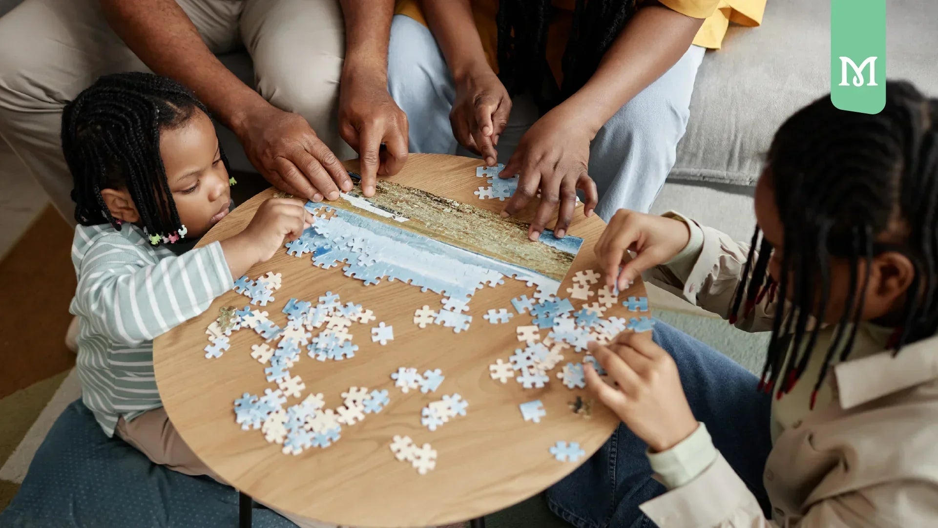 black family making a puzzle on a table with the kids on front